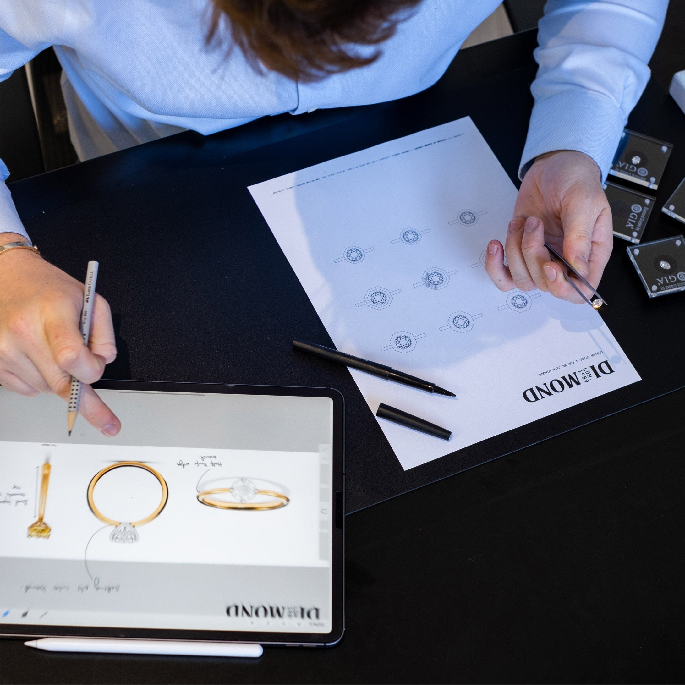 Person working on jewellery design with a tablet and paper, featuring Dimond London branding.