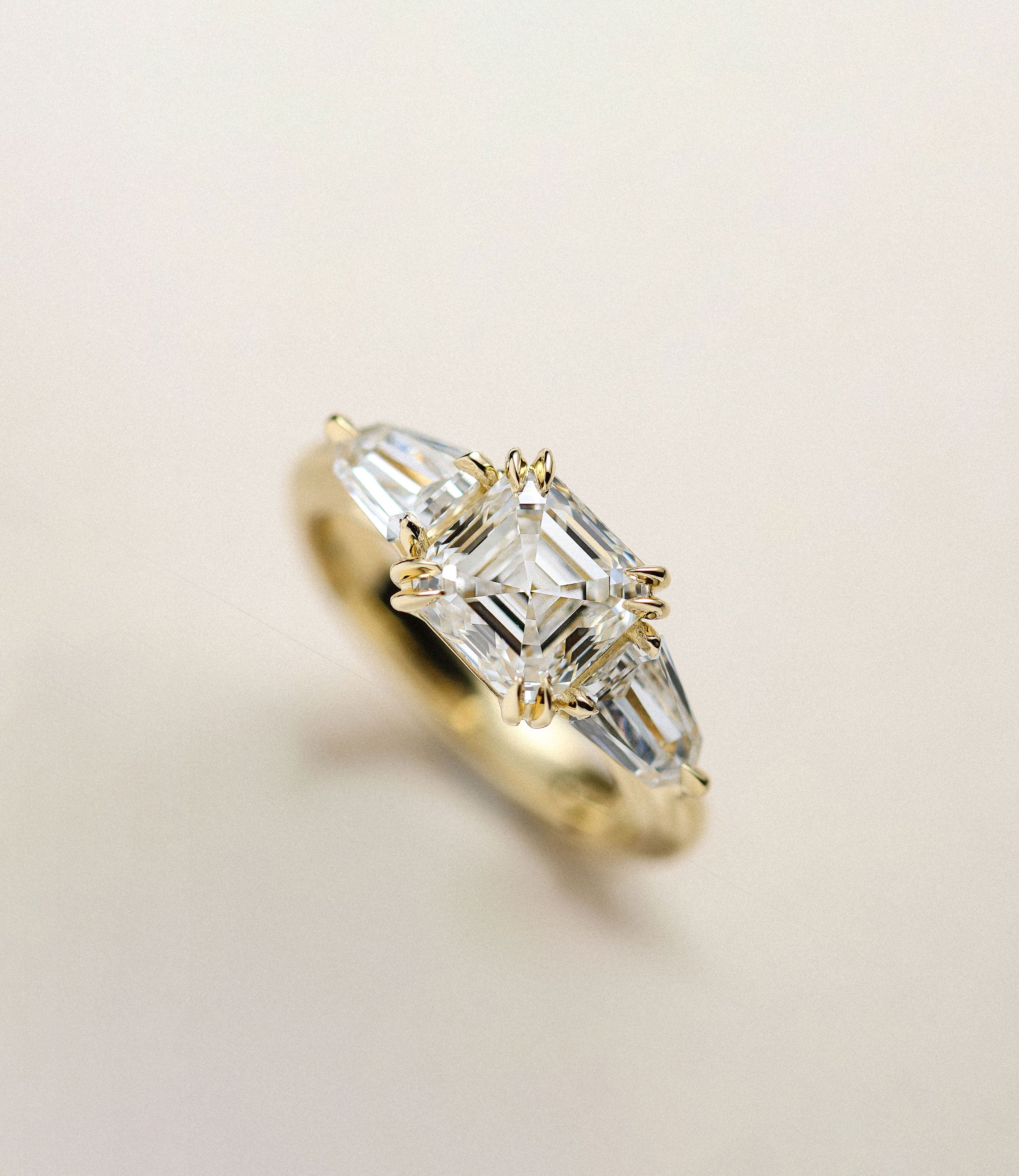 Art Deco Asscher cut diamond trilogy engagement ring set in gold.