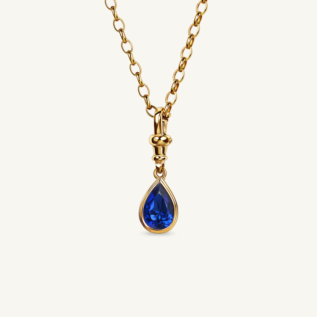 Pear cut royal blue sapphire pendant necklace set in yellow gold.